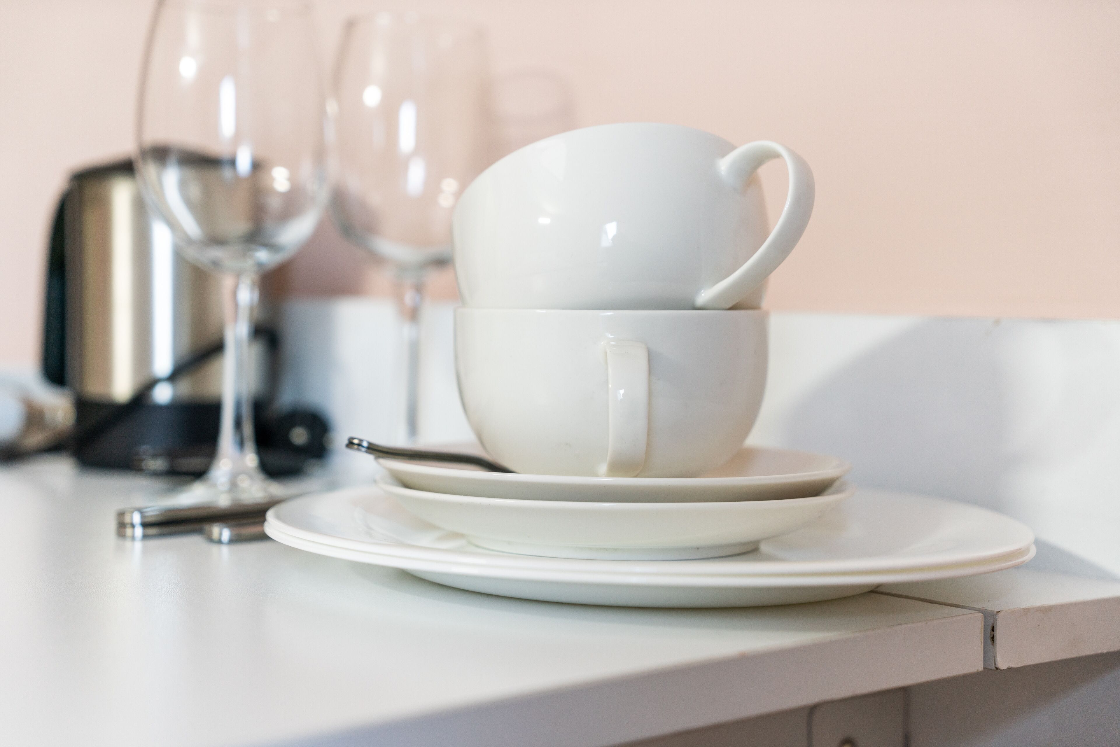 A stack of white cups and saucers on a white table.