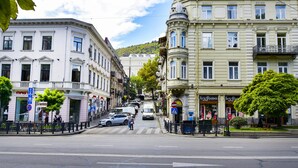 Vista de una calle con edificios, un paso de peatones y coches aparcados.