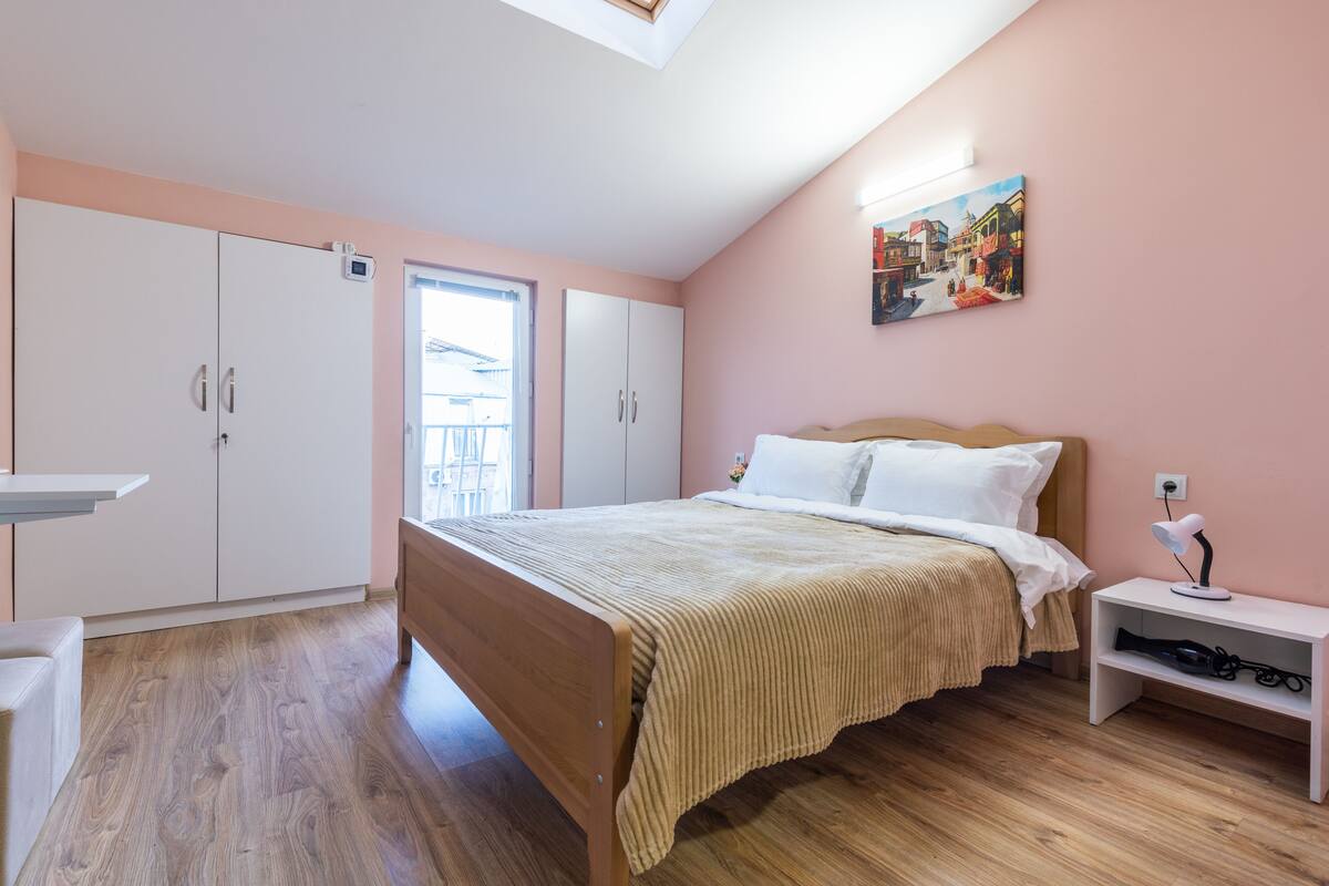 Un dormitorio con cama, mesita de noche, armario y ventana.