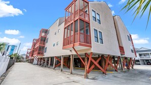 A multi-story building with a red balcony structure, supported by wooden stilts, under construction or renovation.