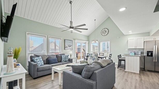 A spacious living area with a gray sofa, a coffee table, and a dining area with a chandelier.