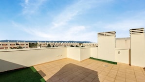 Terraza en la azotea con suelo de baldosas y zona de césped.