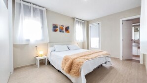 Un dormitorio con cama, mesitas de noche, un plaid suave y obras de arte en la pared.