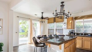 A spacious kitchen with a large island, dark wood cabinets, and a ceiling fan. - Cozy Home in Gated Country Club (Indio)