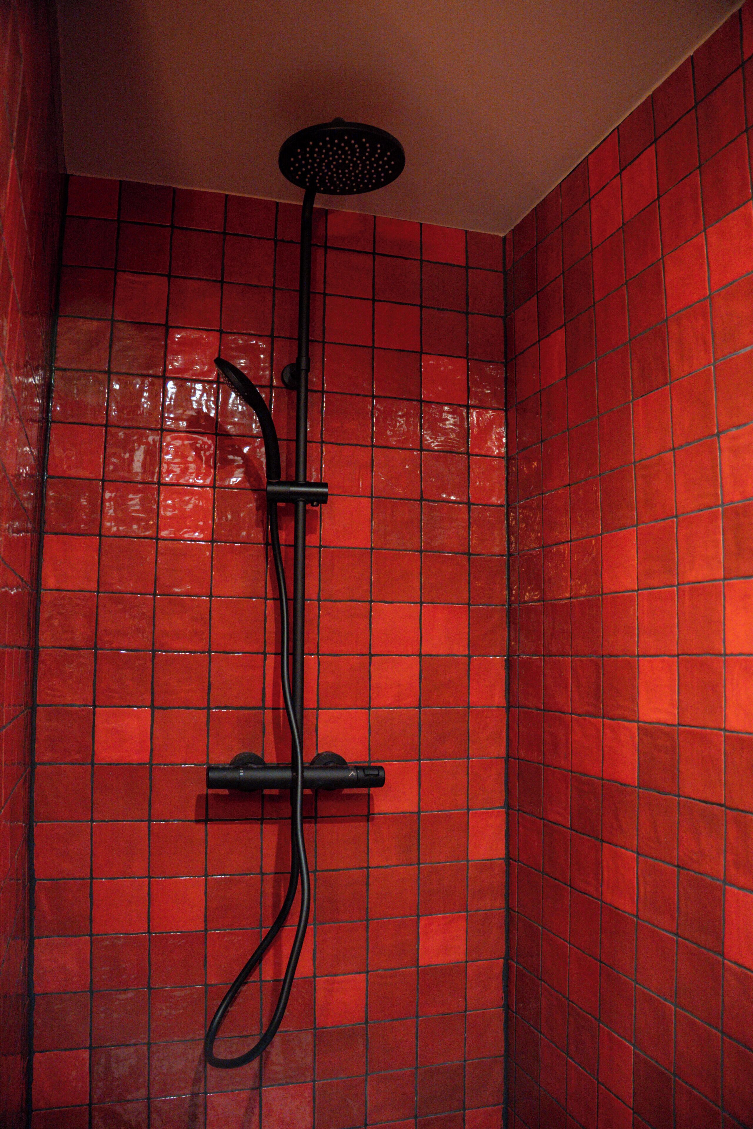 A shower with a handheld showerhead and a wall-mounted control panel.