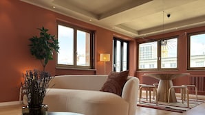 A modern living room with a beige sofa, a round table, and a potted plant. - The Charming by Curt Suites (Berlin)
