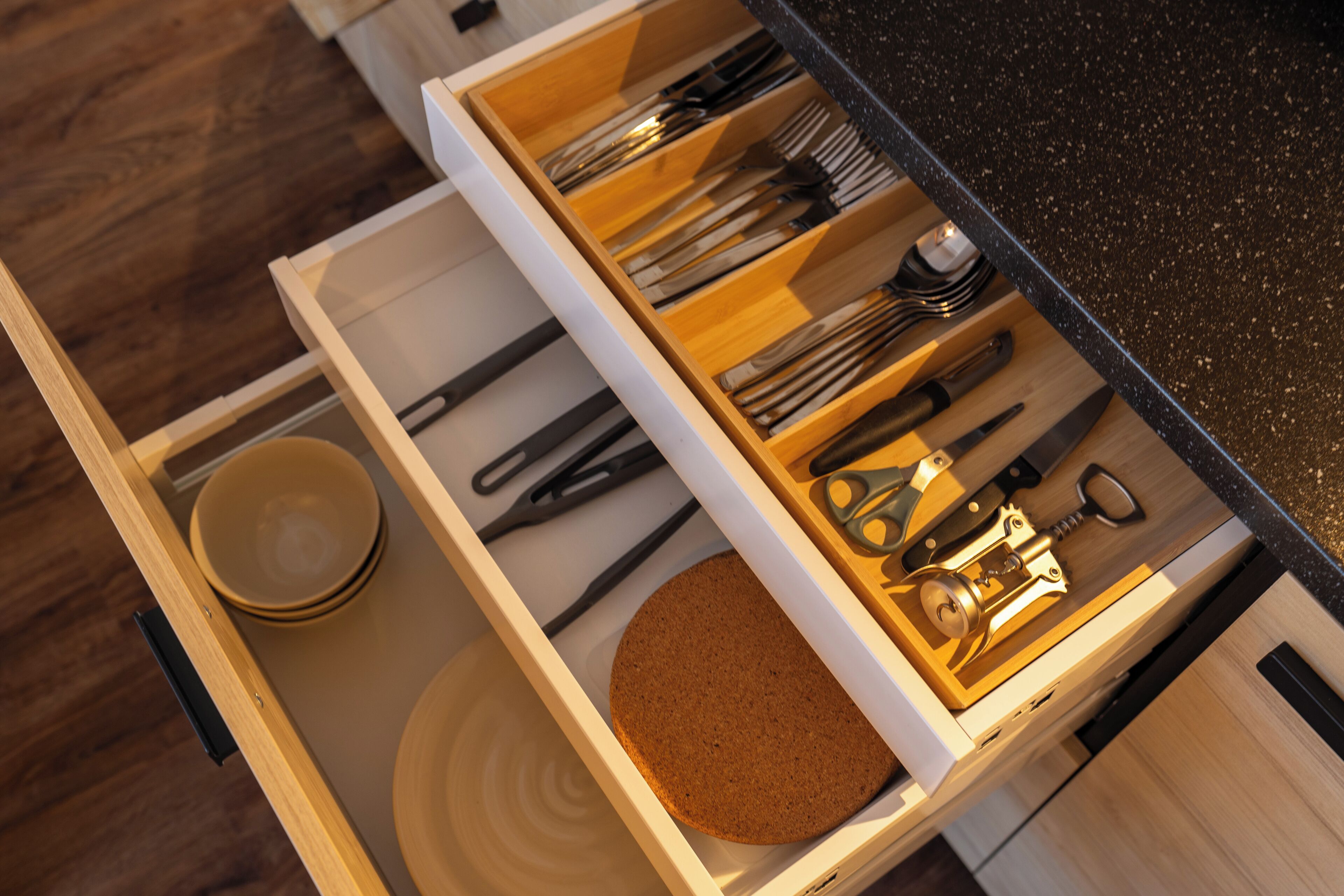 A drawer with kitchen utensils, a cork, and a bowl.
