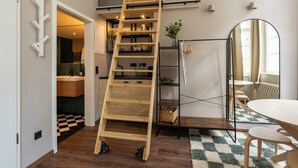 A room with a wooden ladder, a dining table, and a mirror. - The Charming by Curt Suites (Berlin)