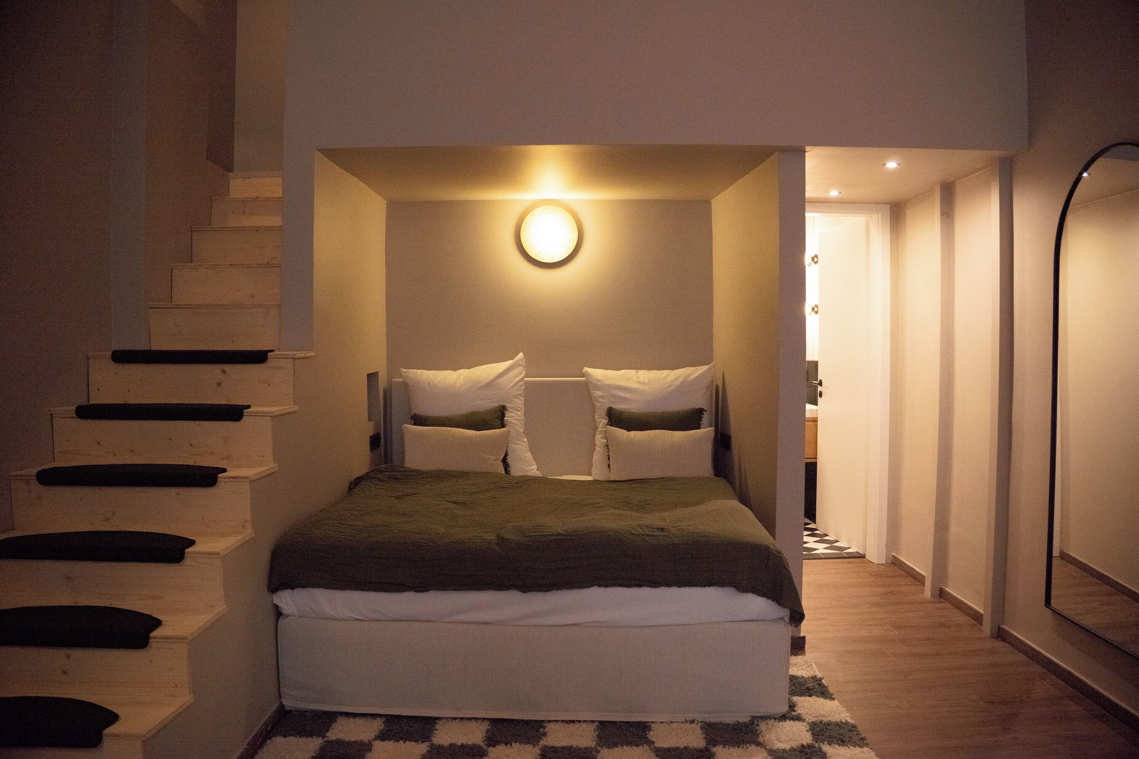 Une chambre à coucher avec un lit, un escalier et un luminaire circulaire.