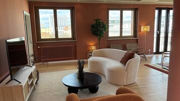 A modern living room with a sofa, armchairs, a coffee table, and a TV.