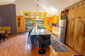 Una cocina moderna con una isla central, taburetes de bar, armarios de madera y un refrigerador grande.