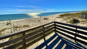 A wooden deck overlooking a beach with a clear view of the ocean and distant shoreline. - Beachfront in Surfside Shores (Gulf Shores)