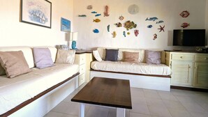 Ein Wohnzimmer mit einer Couch, einem Couchtisch und Wanddekorationen, darunter Fische und ein Gemälde.