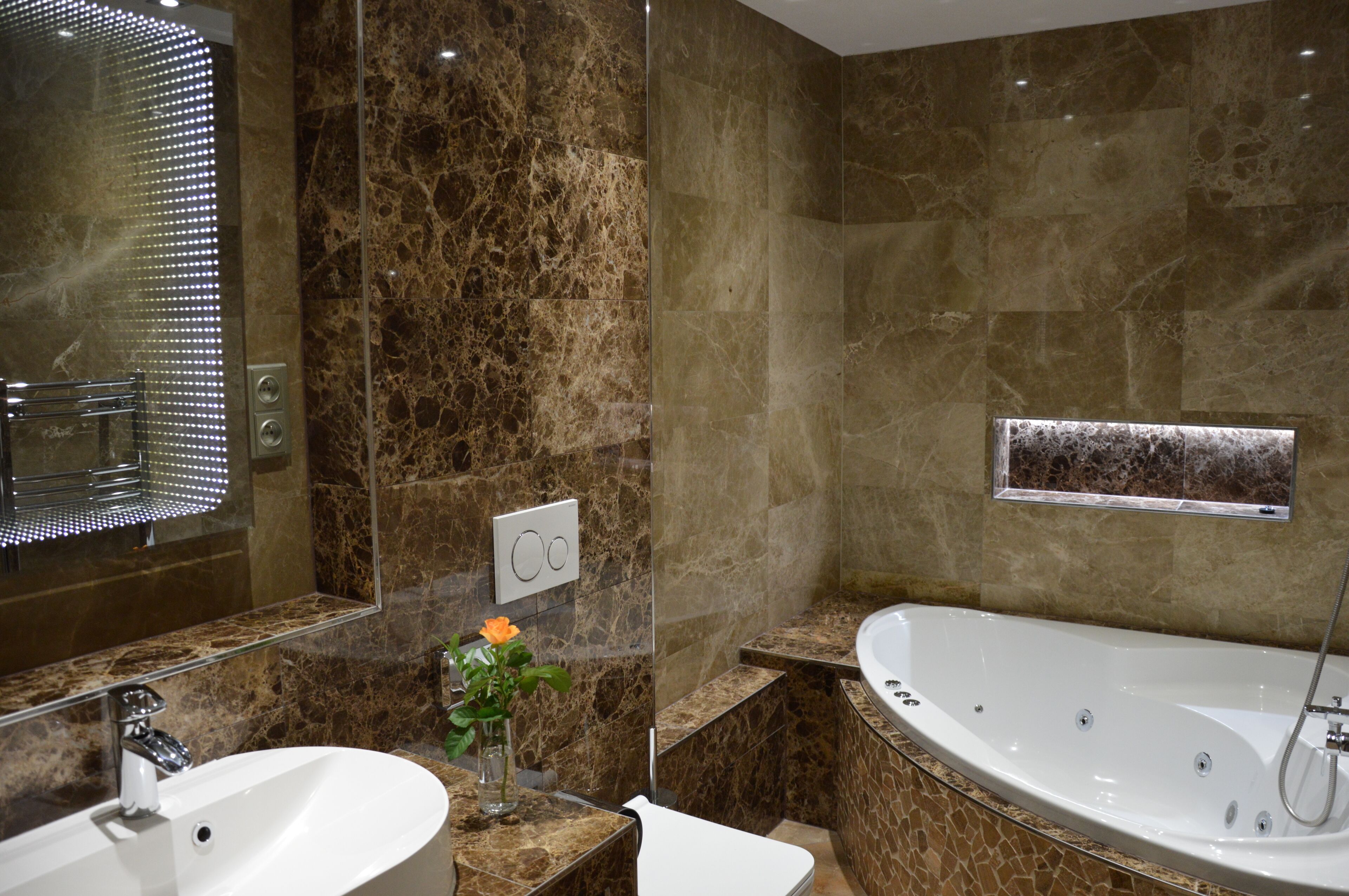 A modern bathroom with a large bathtub, a sink, and a mirror.