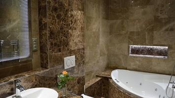 A modern bathroom with a large bathtub, a sink, and a mirror.