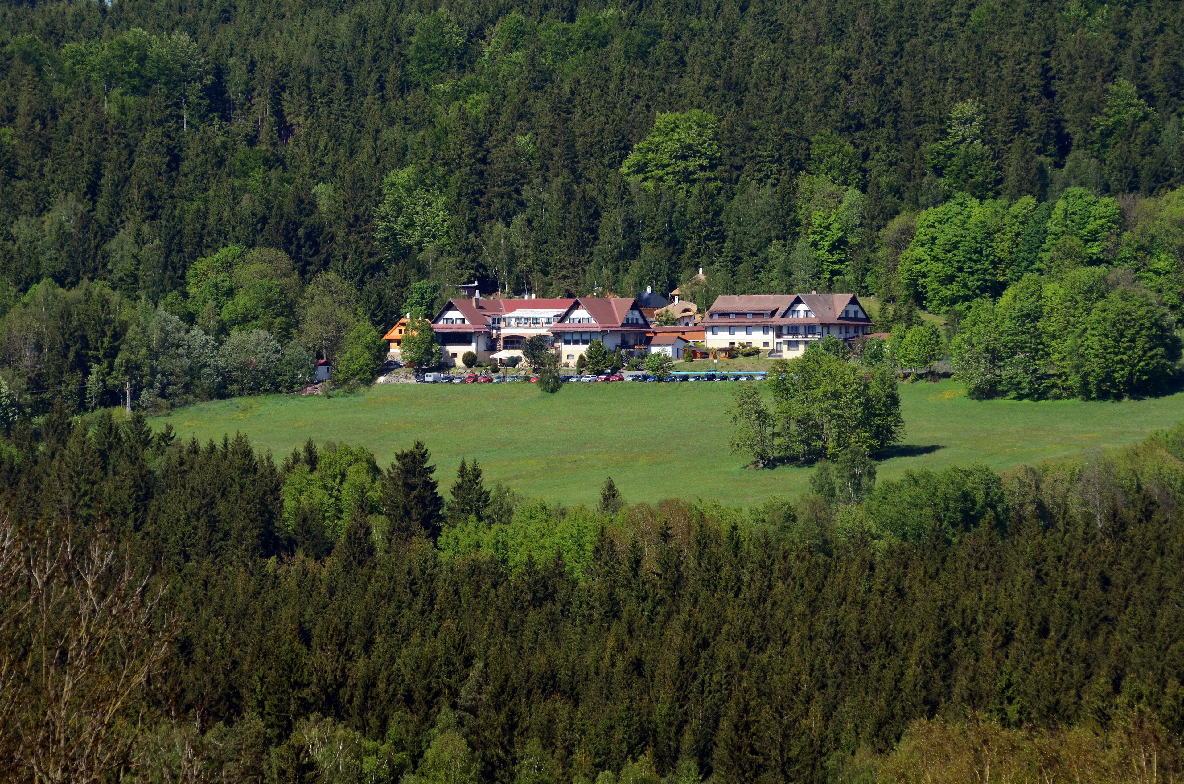 Un grand immeuble à étages, de style architectural traditionnel, entouré d’une forêt dense.