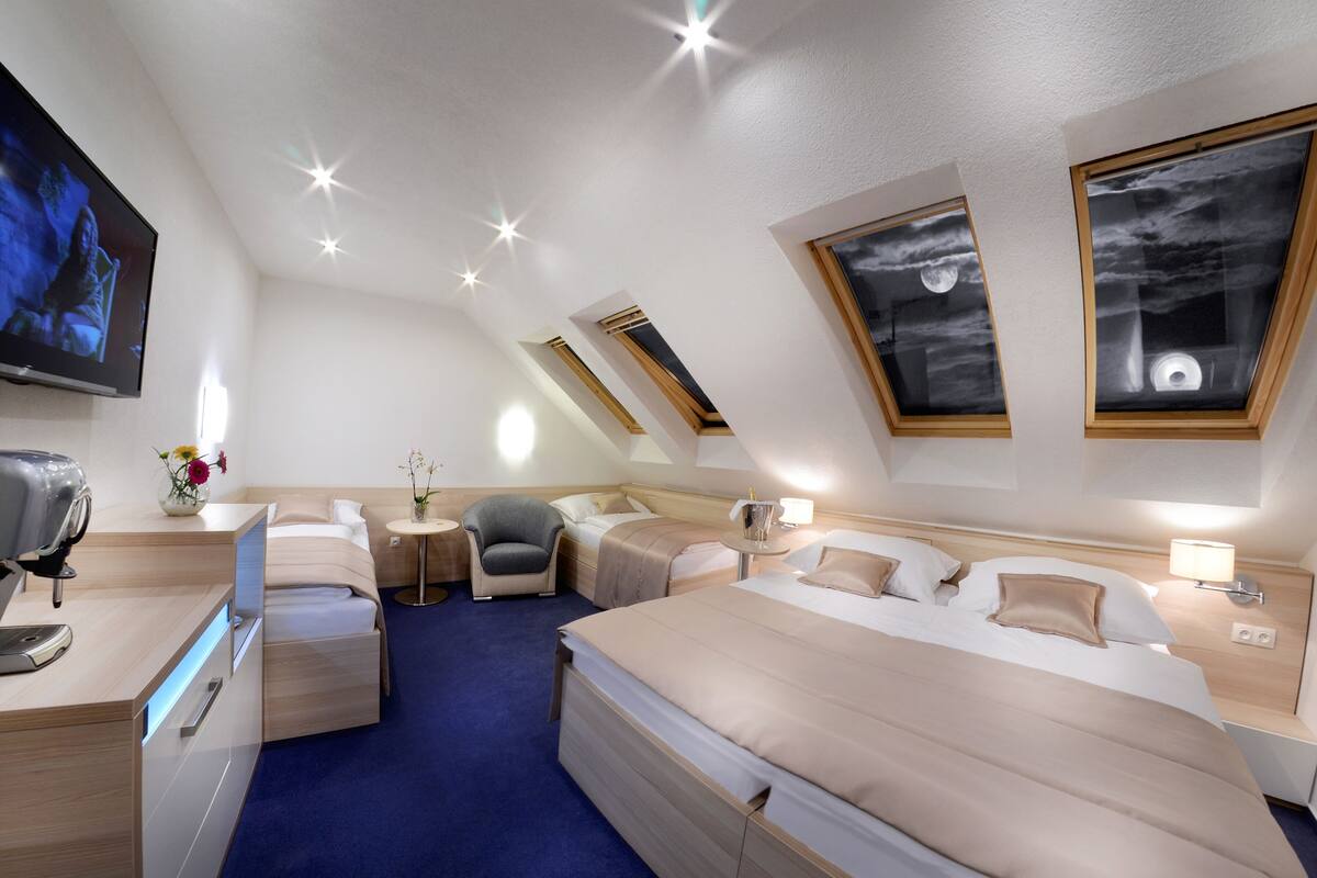 Una habitación de hotel moderna con una cama grande, un escritorio, una silla, un televisor y una pequeña mesa con flores.