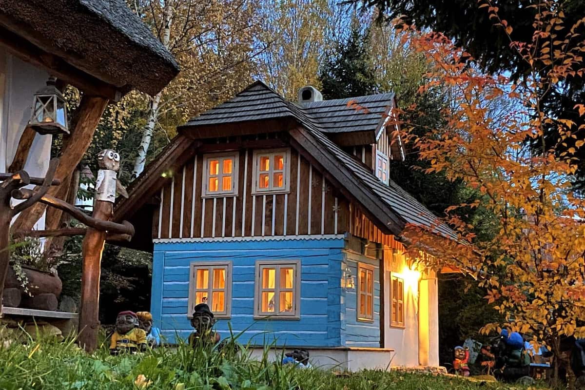 Una casa de madera tradicional con un techo a dos aguas pronunciado, varias ventanas y una iluminación exterior.