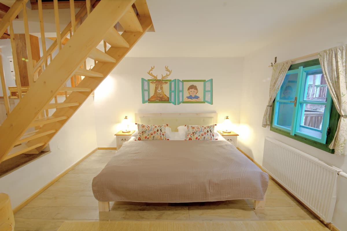 Un dormitorio con una cama grande, una escalera de madera y una ventana con cortinas.