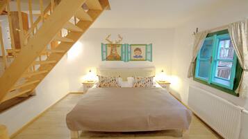 A bedroom with a large bed, wooden staircase, and a window with curtains.