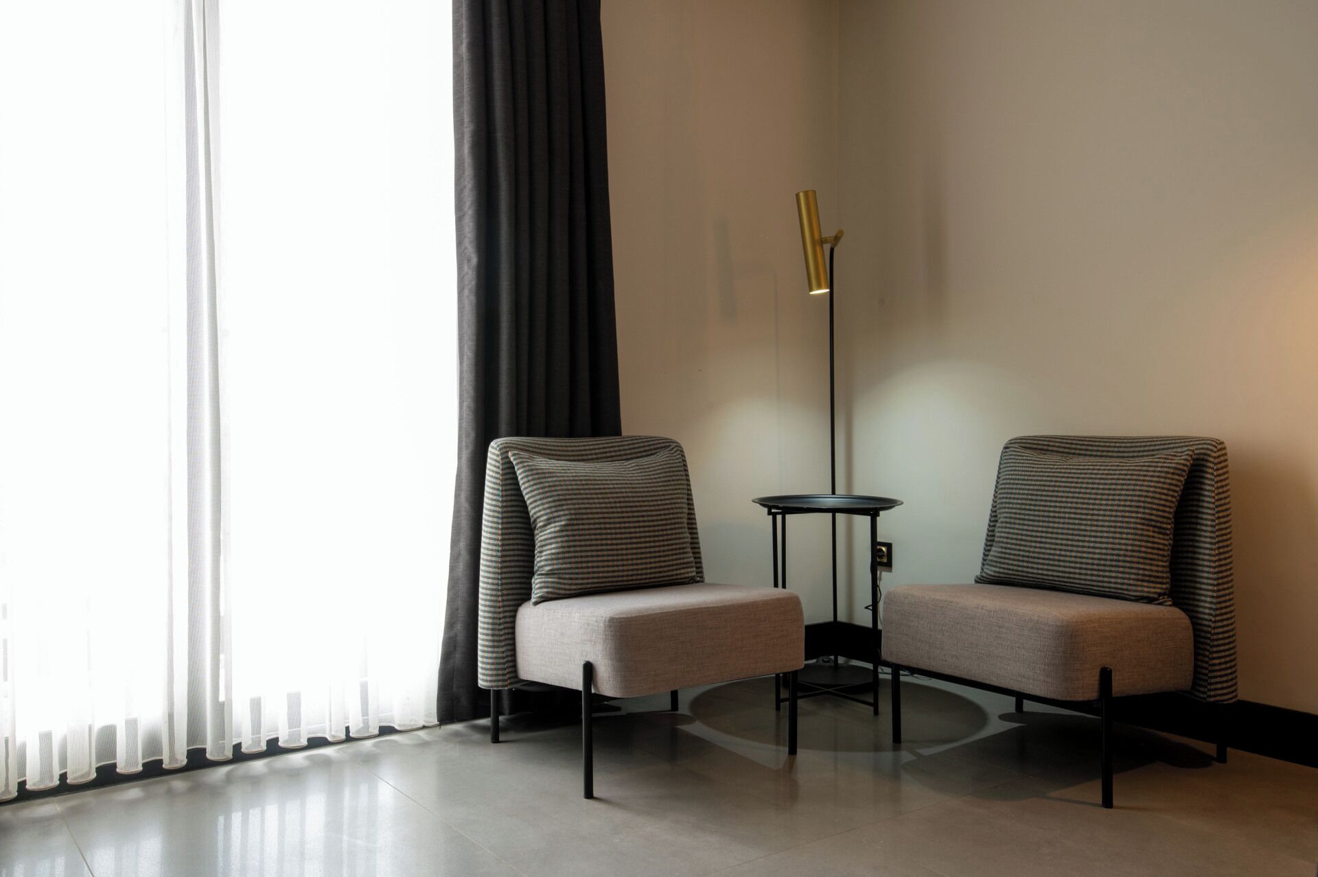A modern room with two armchairs, a floor lamp, and a small table.