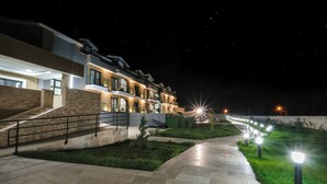 Un hotel moderno con un área exterior bien iluminada, una escalera y un sendero bordeado de luces.