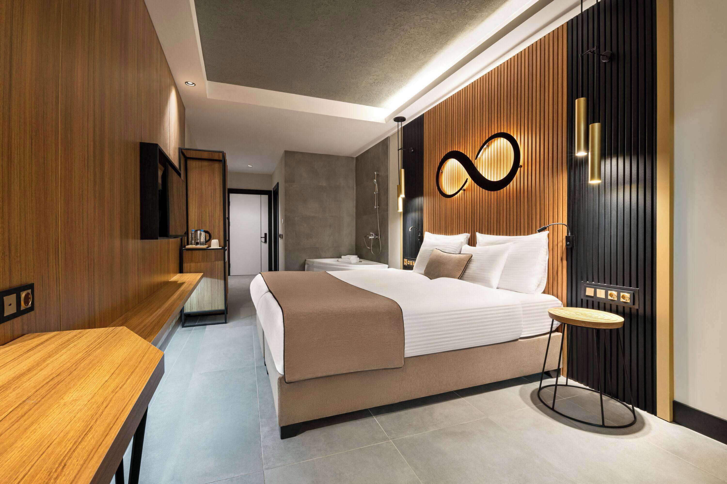 A modern bedroom with a bed, bedside table, and a wall-mounted light fixture.