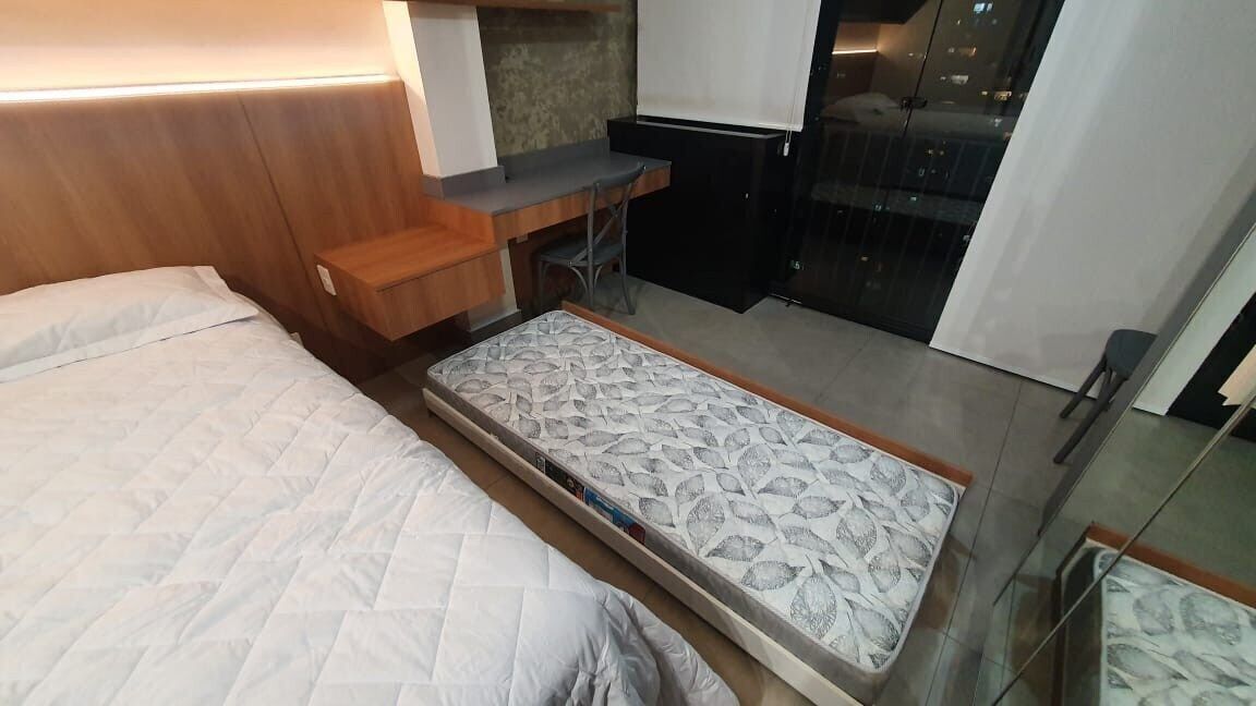 Habitació petita i senzilla amb llit, escriptori i porta corredissa que dona a un balcó.