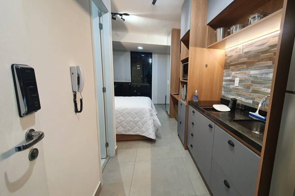 Une chambre d’hôtel moderne équipée d’une kitchenette, d’un lit, d’un téléphone et d’une porte.