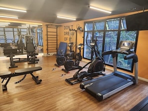 A gym with various exercise equipment, a bench, and a motivational quote on the wall.