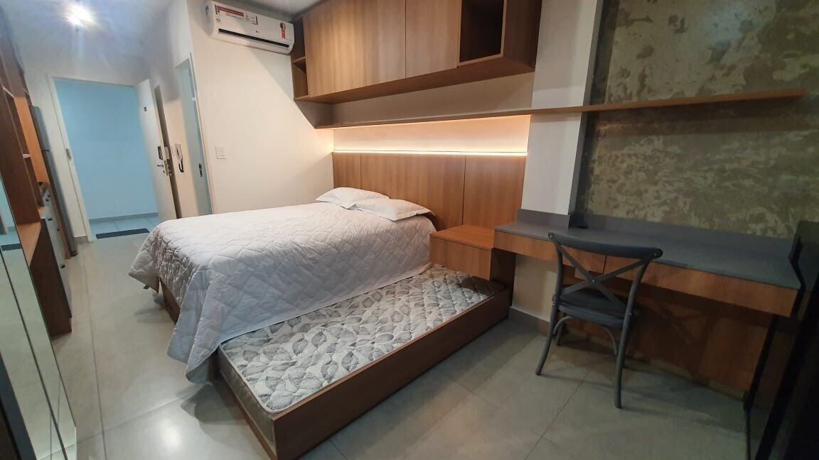 Een kleine slaapkamer met een bed, een bureau en een stoel.