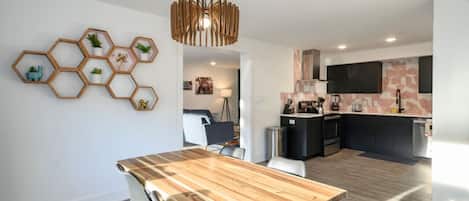 Una cocina moderna con una isla central, un comedor con mesa de madera y un adorno hexagonal con plantas.