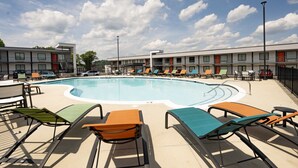 Une piscine avec des chaises longues et un bâtiment en arrière-plan.