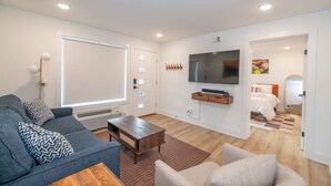 Un salon moderne avec un canapé gris, une table basse et un téléviseur fixé au mur.