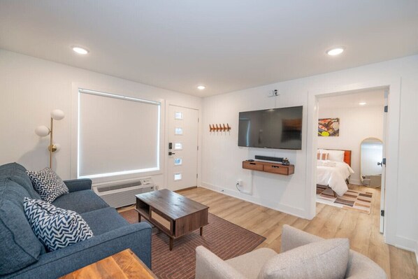 A modern living room with a grey sofa, a coffee table, and a TV mounted on the wall.