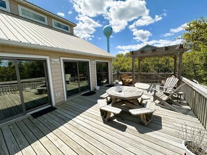 Um deck de madeira com mesa e cadeiras, uma pérgula e um gazebo.