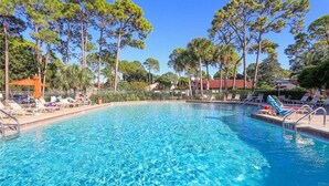 A clear blue pool surrounded by lounge chairs and umbrellas, with trees and buildings in the background. - Serene retreat awaits at prime location in charming Timberwoods/Village des Pins (Sarasota)