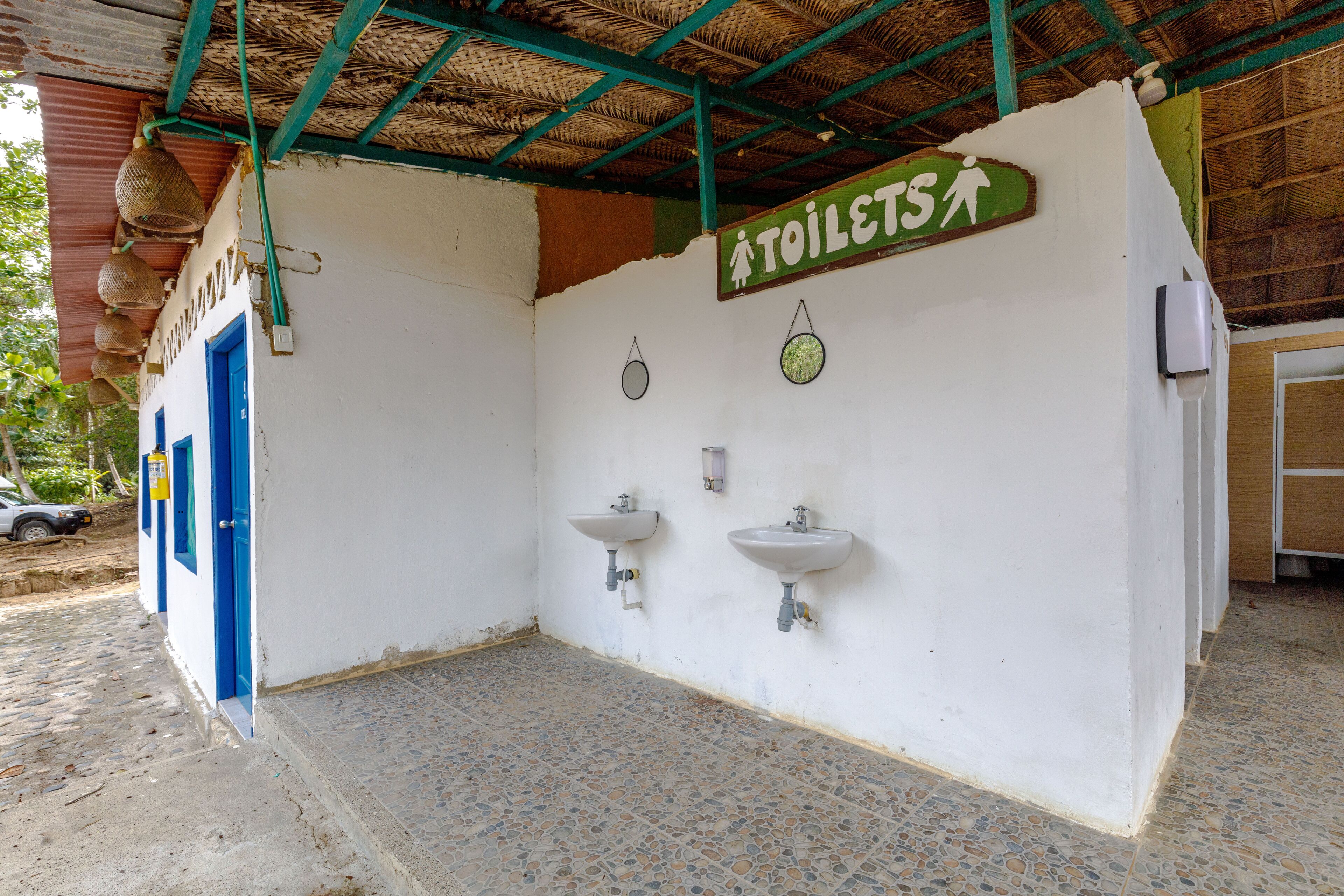 A public restroom with two sinks, a blue door, and a sign indicating the location of toilets.