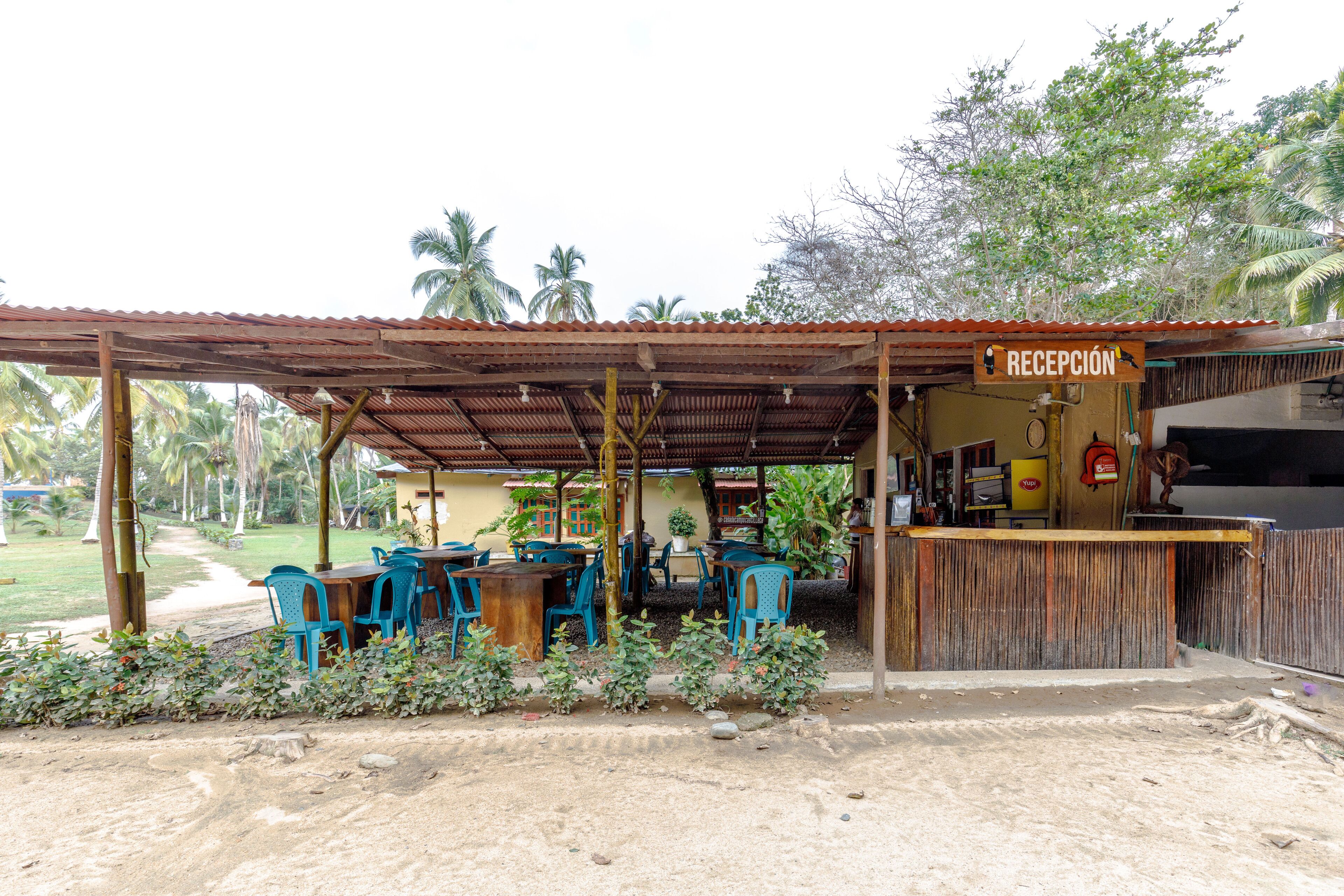 A reception area with a sign, outdoor seating, and a dirt path.
