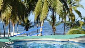 A swimming pool with a blue deck, surrounded by palm trees and overlooking the ocean. - CASA DE CAMPO CASTILLETE (Santa Marta)