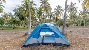 A blue and white tent with a bed inside, surrounded by palm trees. - CASA DE CAMPO CASTILLETE (Santa Marta)