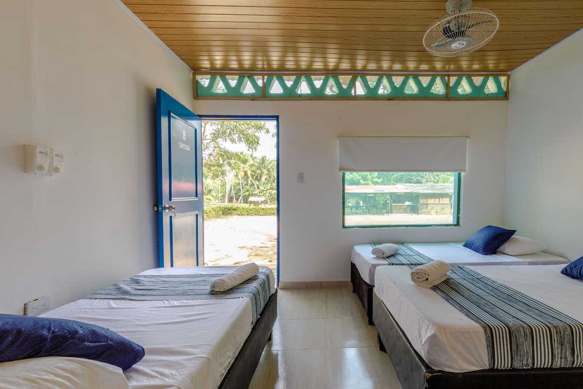 A room with two beds, a window, and a door leading outside.