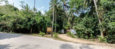 A paved road with a dirt path leading to a signboard.