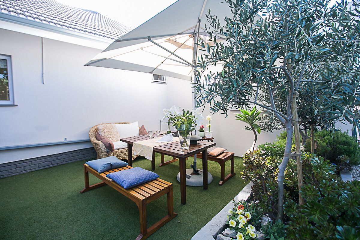 A patio with a wooden table, a cushioned chair, and a bench.