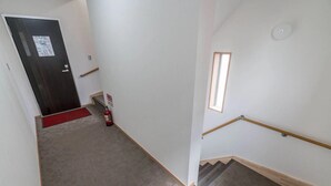 A staircase with a wooden handrail, carpeted steps, and a fire extinguisher on the floor.