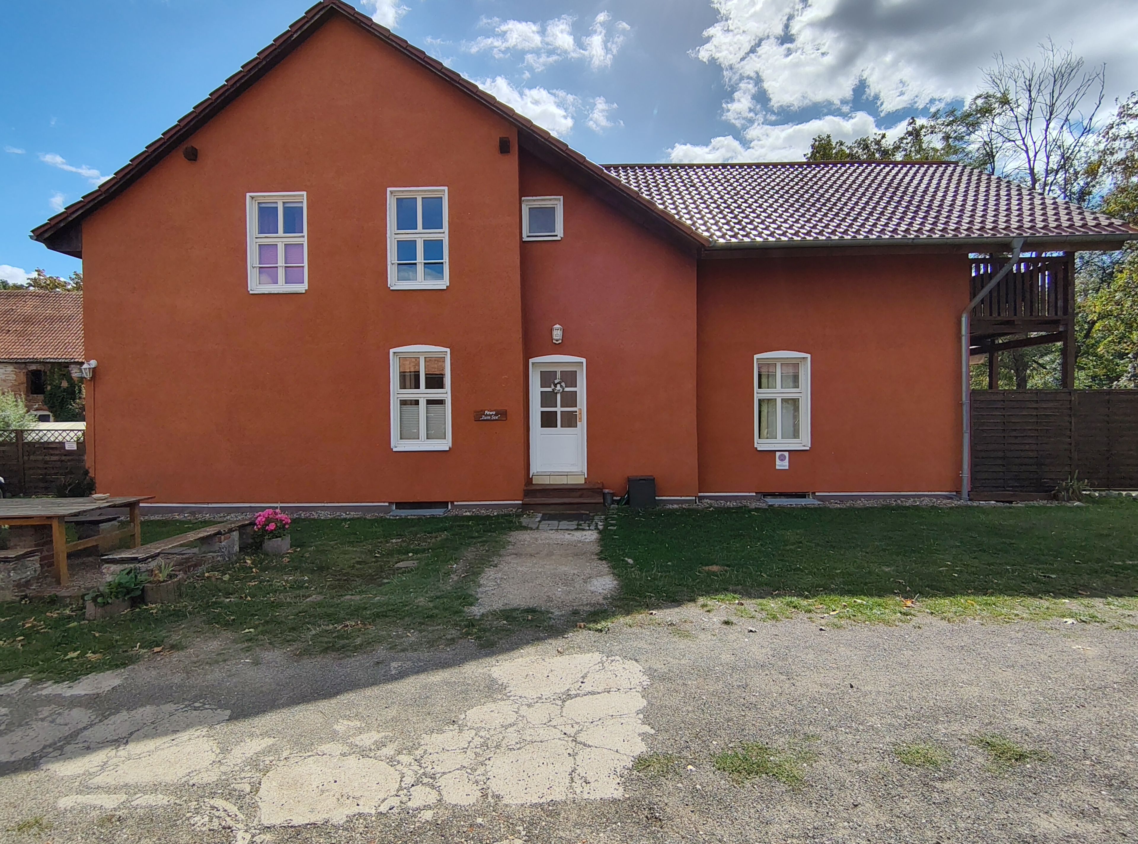 A two-story house with a red exterior, a front door, and multiple windows.