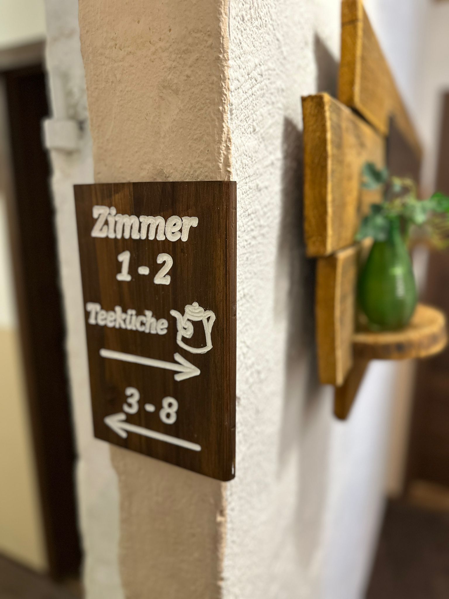 A sign indicating room numbers 1-2 and 3-8, with a directional arrow pointing to the right for the kitchen.