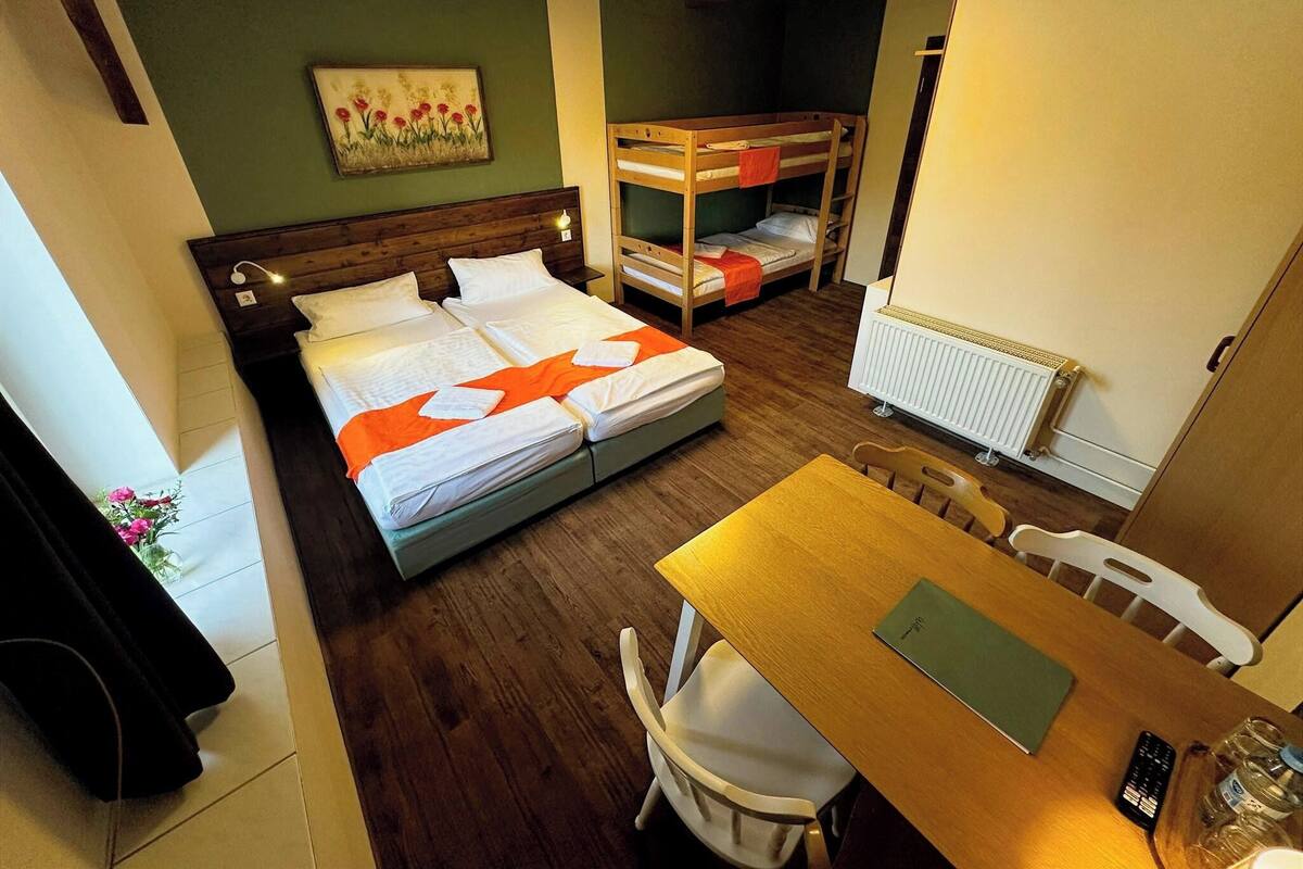 Um quarto com uma cama beliche, uma cama de solteiro, uma mesa de madeira e uma cadeira.