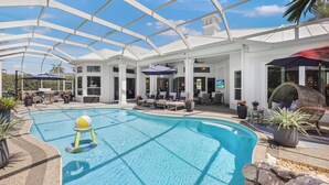 A pool area with a glass ceiling, lounge chairs, and umbrellas.