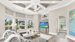 A spacious living room with a grey sofa, a wooden coffee table, and a flat-screen TV.